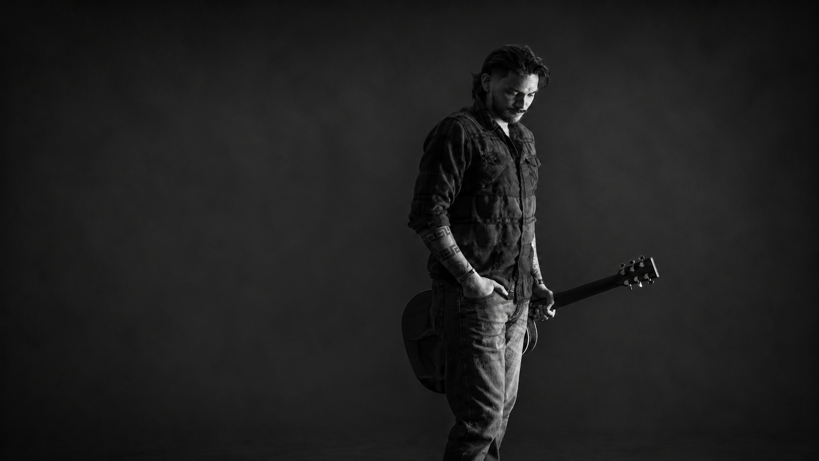 Anthony Segovia holding a guitar in a centered black-and-white portrait
